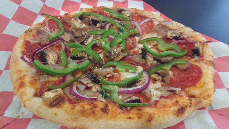 Photo of a pizza with pepperoni, onions, mushrooms, and green peppers in a pizza box.