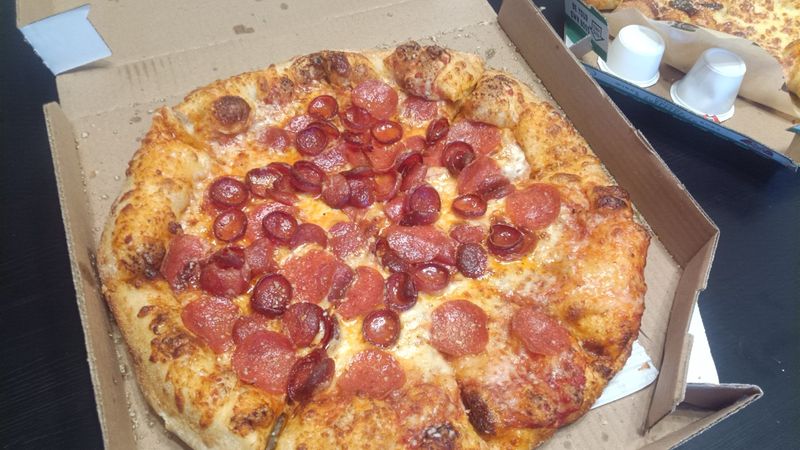 Photo of a pizza in a box, with multiple kinds and sizes of pepperoni.