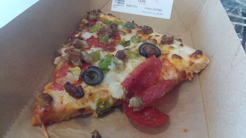 A slice of supreme pizza on a cardboard tray.