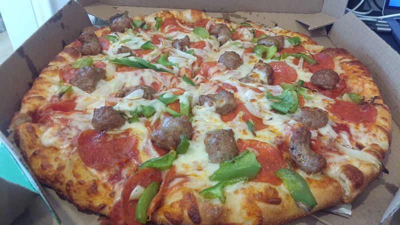 Photo of a pizza with pepperoni, sausage, and green peppers in a pizza box.