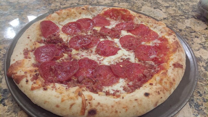 Photo of a pizza with pepperoni and bacon.