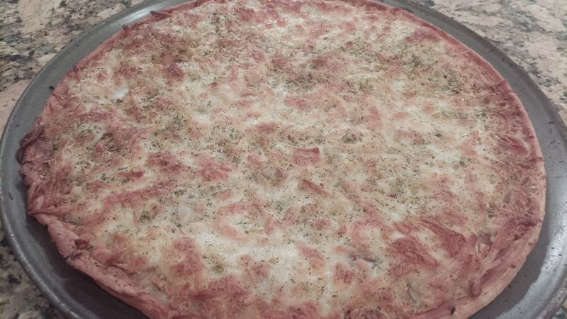 A photo of a cheese pizza on a pan, on a granite countertop. The cheese is crispy and the thin crust is browned.