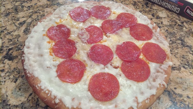 A photo of a cheese and pepperoni pizza, on a granite countertop.