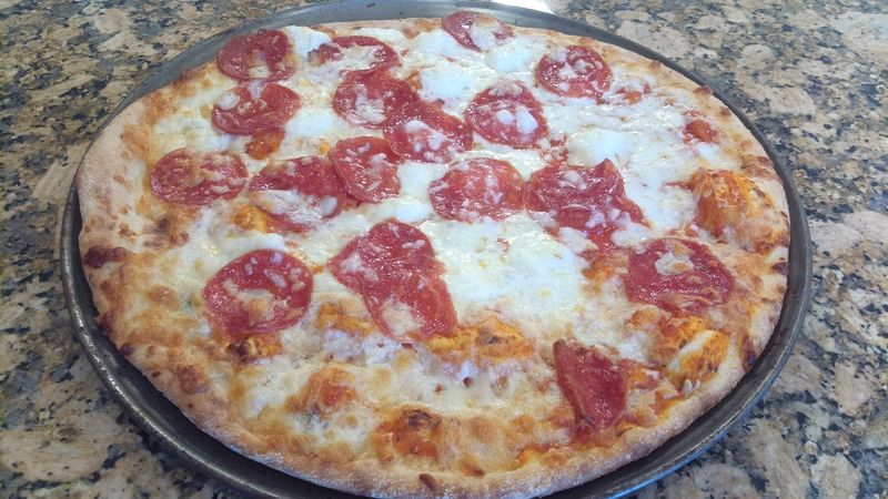 Photo of a thin crust pizza with pepperoni and ricotta cheese.